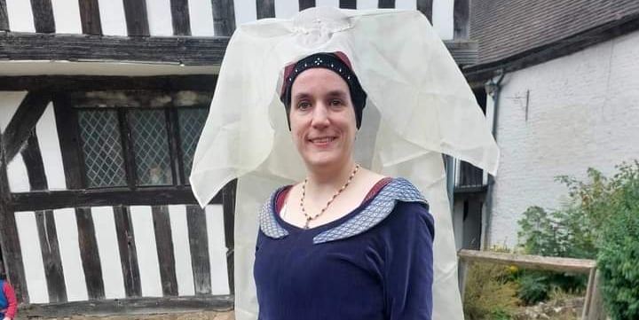 a woman in a medieval costume standing in front of a house