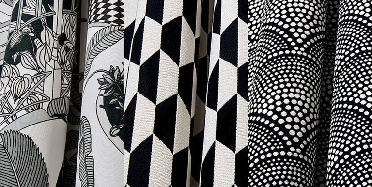 Black and white patterned upholstery fabric samples featuring geometric, floral, and dotted designs.