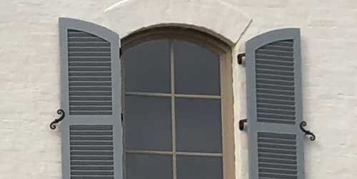 fixed louver shutters with decorative hardware to open and close and protect