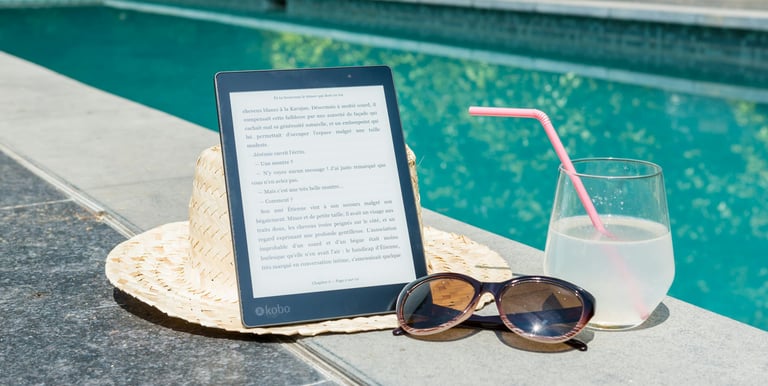 a tablet with a straw hat and sunglasses next to a book