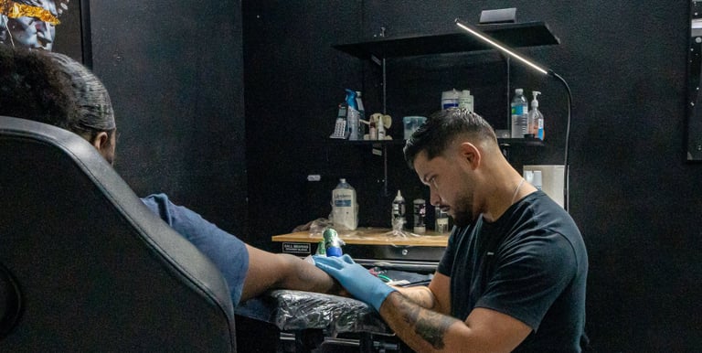 tattoo artist giving a tattoo to client in private tattoo booth