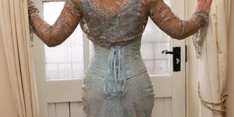 a woman in a blue corset and lace top standing in front of a door