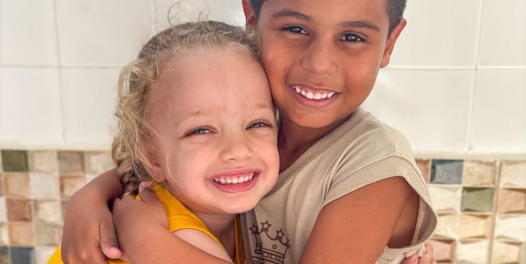 a boy and girl hugging each other on a tiled floor