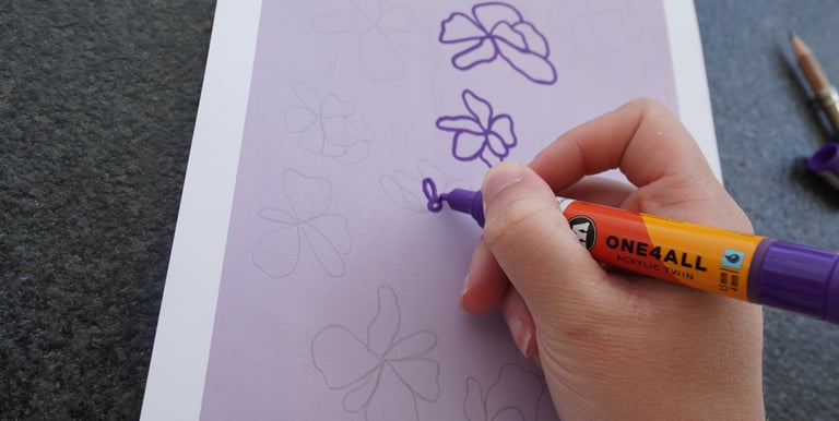 Hand drawing a custom floral pattern design with a purple marker.