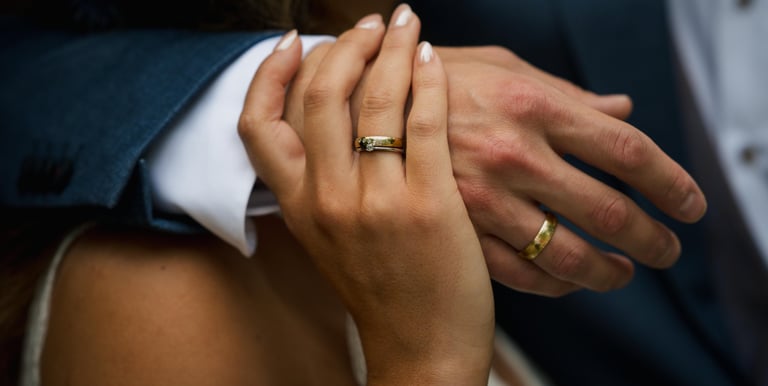a man and woman holding hands and wearing wedding rings