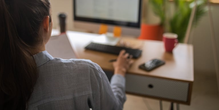 a woman sitting at a desk with a computer and a ball