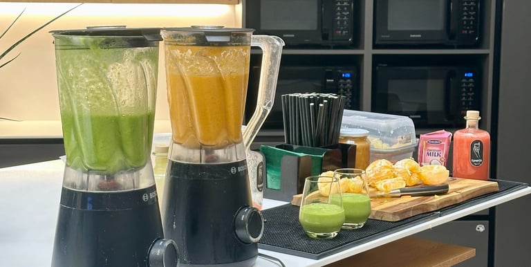 Mobilus vaisių baras ofise – šviežiai pagaminti žali ir oranžiniai smoothie