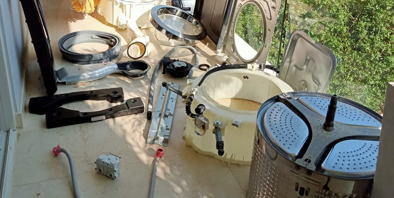 Partes de lavadoras y repuestos sobre una mesa, ilustrando el servicio técnico de reparación