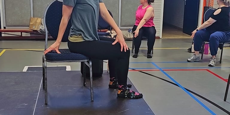 Dames in een zittende twist, op een stoel, in een gymzaal