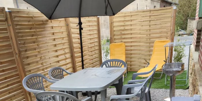 Terrasse ensoleillée avec salon de jardin et parasol. Parfaite pour les repas en plein air. Location de vacances