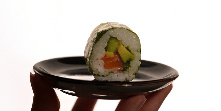 un sushi posé sur une assiette avec un fond blanc très lumineux