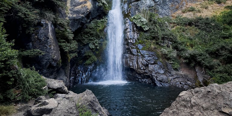 Imponente caída de agua rodeada de bosque nativo y vegetación en la ruta de cascadas de Lonquimay.