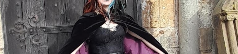 a woman in a black dress wearing a purple lined velvet cloak