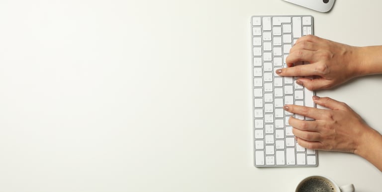 Mains de professionnelle tapant sur un clavier Apple blanc — rédaction de contenu stratégique et communication numérique