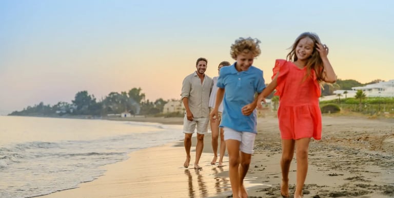 A happy family with young children walking on a sandy beach during a golden sunset vacation.