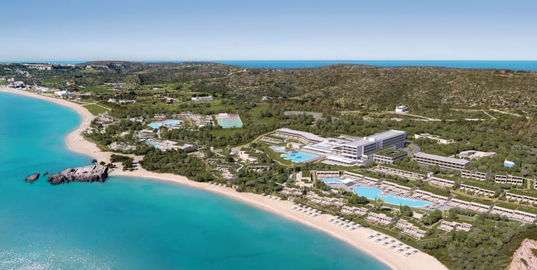 Aerial view of a luxury beachfront Ikos Aria, turquoise ocean water, and sandy beach.