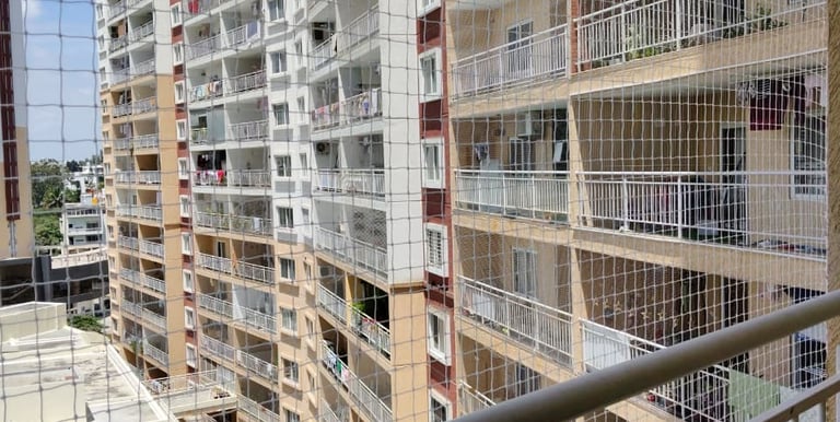 Close-up of a securely fastened balcony safety net with a cityscape background.