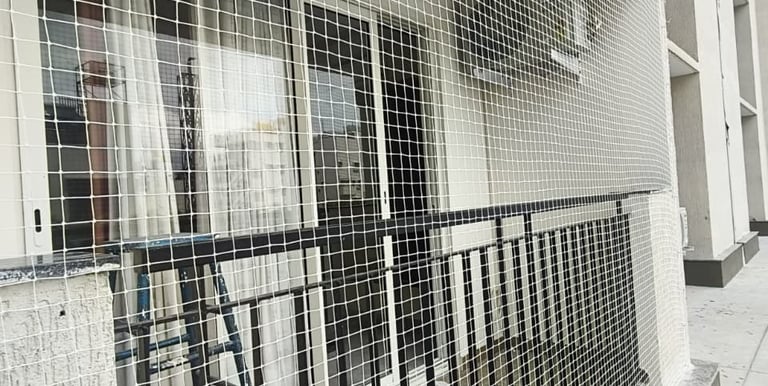 Technician carefully installing a sturdy safety net on a high-rise balcony in Bengaluru.