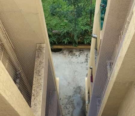 Technician carefully installing a durable safety net over a duct area in a Bannerghatta building.