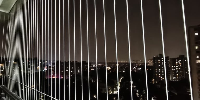 Wide shot of a modern apartment balcony in Bengaluru fitted with transparent safety grills.
