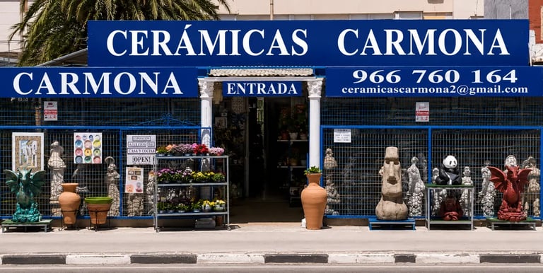 Ceramicas Carmona storefront in Spain showcasing decorative garden statues and ceramic pottery.
