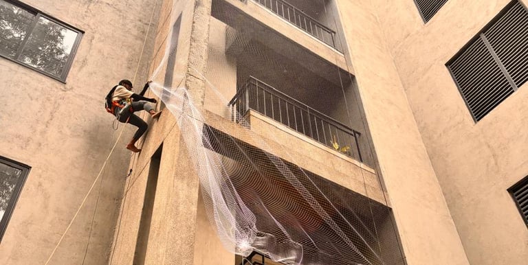 Technician carefully installing a balcony safety net in a high-rise Bangalore apartment.