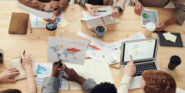 Diverse business team reviewing financial data charts and analytics on laptop during meeting.