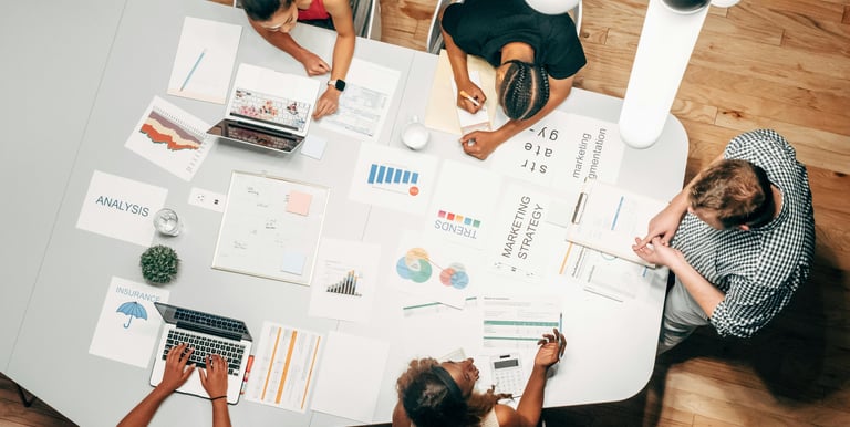 Diverse team collaborating on a marketing strategy and data analysis at a modern office table.