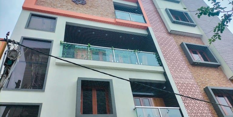 Technician carefully installing a balcony safety net on a high-rise apartment in Pune.