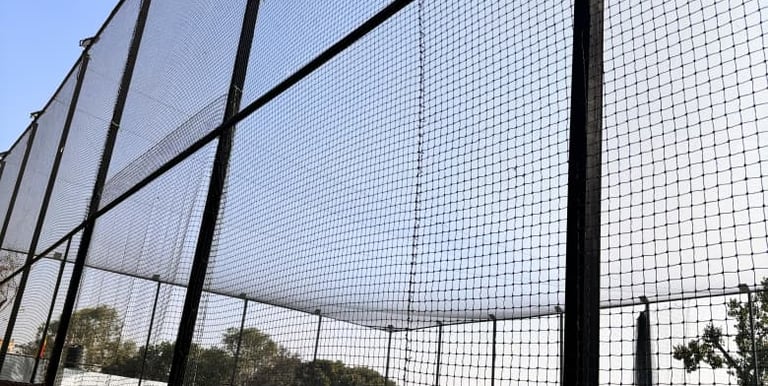 A wide view of a football field with freshly installed protective nets around the perimeter.