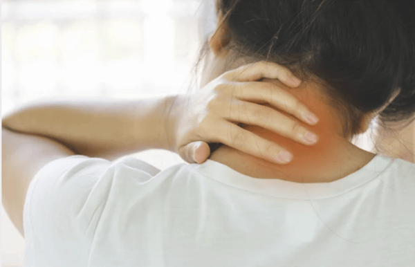 A woman holding her neck in pain, highlighting symptoms of neck strain and cervical spine discomfort.