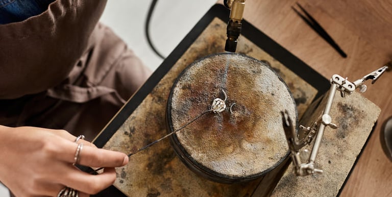 Joyero usando un soplete  para soldar un anillo de plata hecho a mano sobre un bloque de soldadura