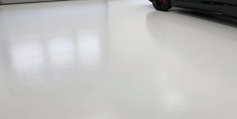 A freshly finished high-end residential garage with glossy metallic epoxy flooring and custom storage solutions.