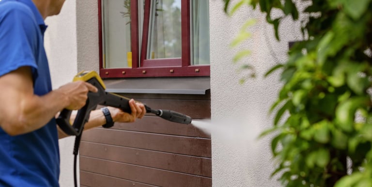 a man in a blue shirt is using a power washer