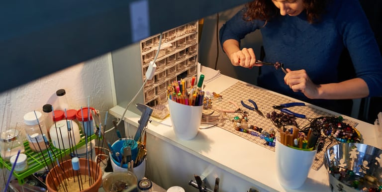Artesano joyero usando pinzas en un escritorio con cuentas y materiales  para el diseño