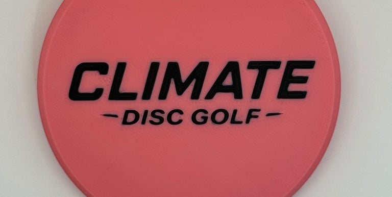 A pink Climate Disc Golf mini marker disc with black embossed lettering on a white background.
