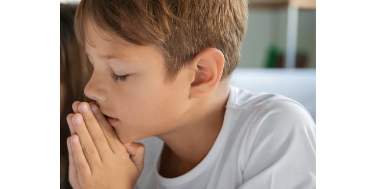 a young boy praying with his eyes closed