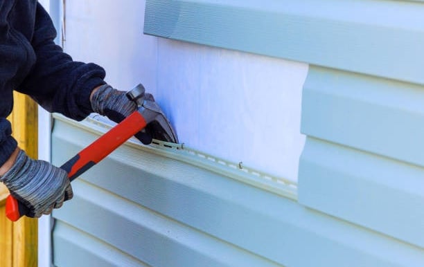 Man replacing siding on a home