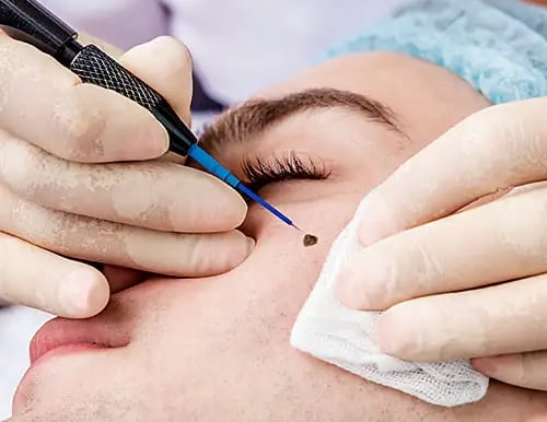 a man getting his eyebrows trimmed up and a woman is getting her eyebrows done