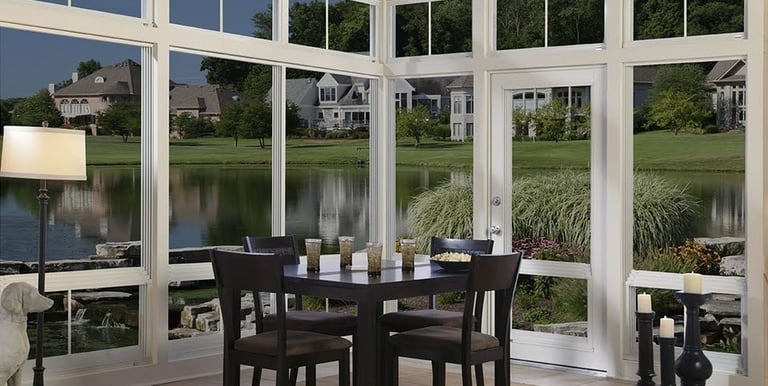Three 3 seasons sunroom a dining room with a table and chairs