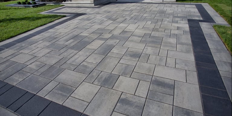 a driveway with light and dark pavers, and a dark border all around
