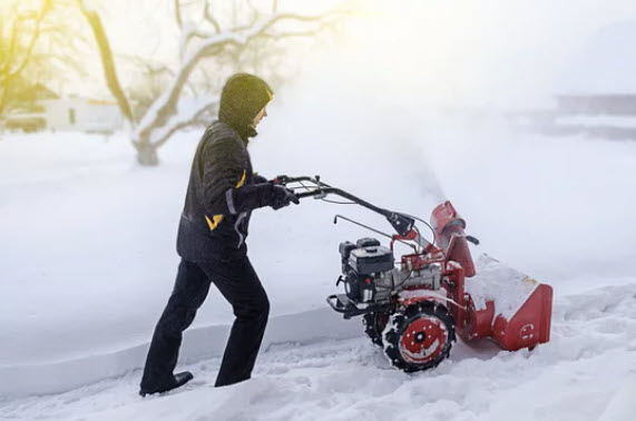 a person using a snow blower to clear snow from the driveway