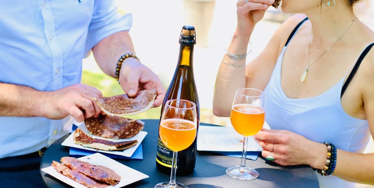 Couple qui déguste des galettes avec du cidre sur une table à l'extérieur