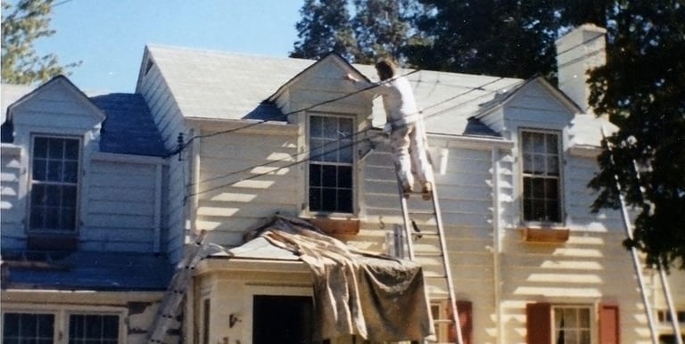a man is painting a house with a ladder