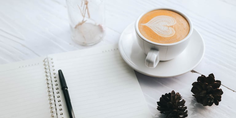 Open Journal page and a cup of coffee on a tabletop
