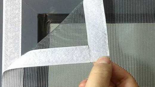 A technician carefully fitting a mosquito net on a window in a bright Sarjapur home.