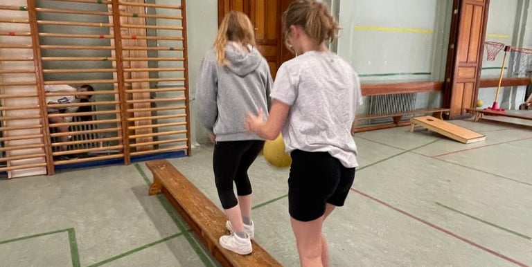 image de 2 élèves marchant sur un banc dans la salle de gymnastique