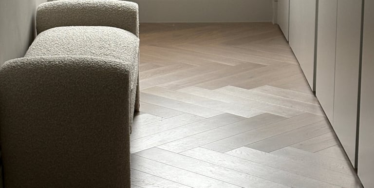A light oak herringbone floor with a small chair