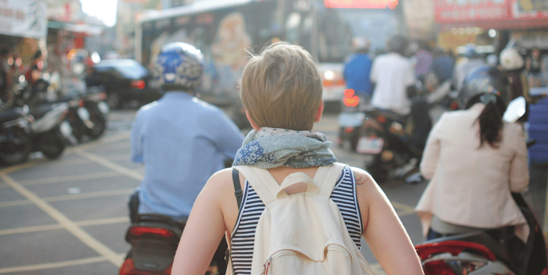 a woman walking down a busy street in a busy city