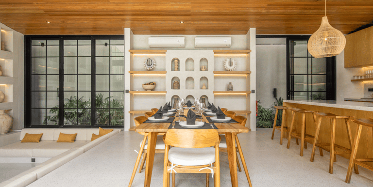 Dining table set in between a sunken lounge and kitchen island with bar stools